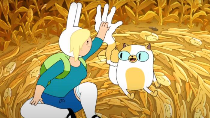Adventure Time: Fionna & Cake: Cake and Fionna are sitting together on a pile of hay. They're high-fiving, and there's an outline of white emphasis outlining their hand/paw as they smack together