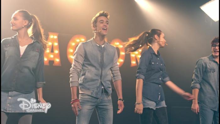 Alex and Co.: An Italian boy stand in the middle of two Italian girls on stage as they sing. 