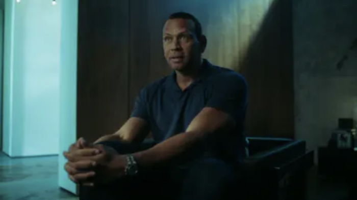 Alex vs ARod TV show screenshot 1: Alex Rodriguez in dark shirt sitting in dark chair in dim light