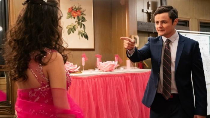 Alternatino with Arturo Castro TV Series: Dressed in a tailored suit, Arturo points his finger at a woman in an elaborate pink dress with her back to us