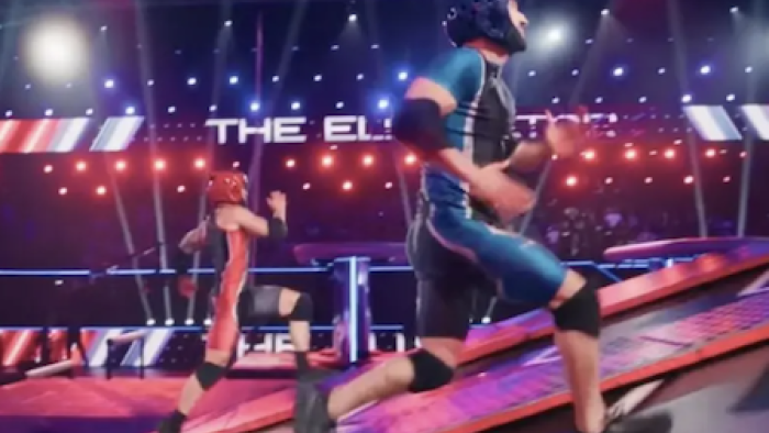 American Gladiators (2026) screenshot 3: A contender wearing red and another wearing blue race up motorized backwards treadmills to the finish line.
