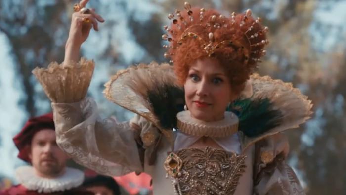 American Princess TV Series: A woman dressed as a queen with an upstanding ruff makes an imperious gesture