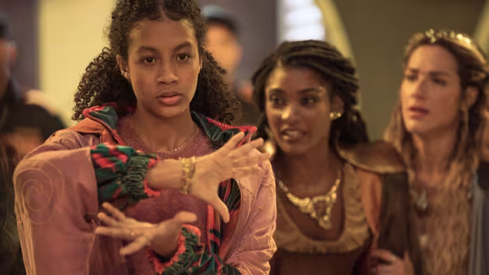 Aruna's Magic TV: Mina holds her hand in opposite directions in front of her, trying to cast a spell. Latifa and Juno cheer her from the back.