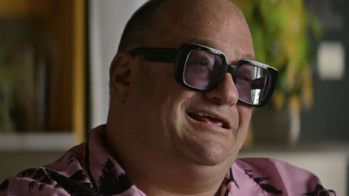 Ashley Madison: Sex, Lies, and Scandal TV show screenshot 1: Evan Banks wears a pink shirt and big black glasses. 