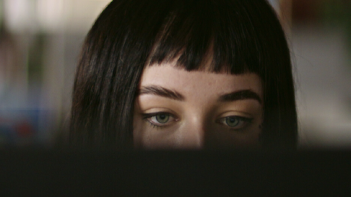Ashley Madison: Sex, Lies, and Scandal TV show screenshot 3: A woman with dark hair and blue eyes behind a computer screen. 