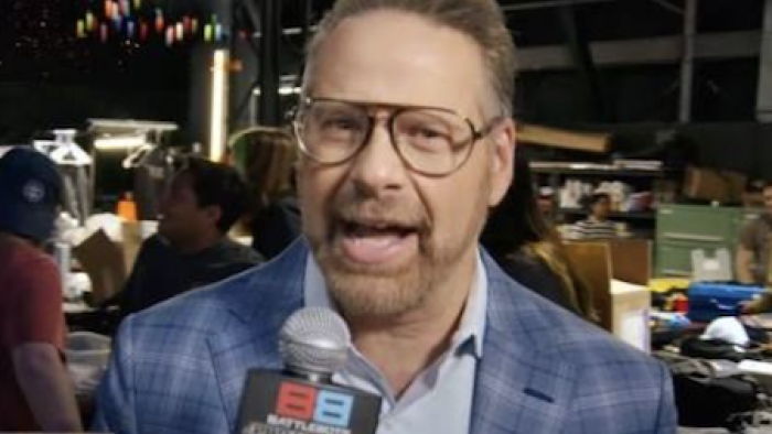 BattleBots Pro League screenshot 1: Chris Rose with glasses speaking into a microphone in a busy, well-lit setting.