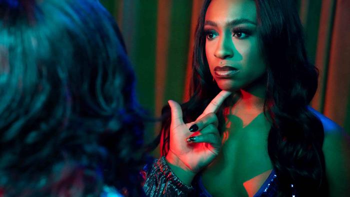 Beauty in Black TV show screenshot 1: A woman uses her finger to hold up Taylor Polidore Williams’ chin. She wears a sequin bikini.