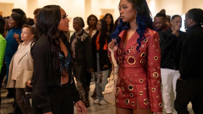 Beauty in Black TV show screenshot 2: (L to R) Taylor Polidore Williams and Amber Reign Smith talk to each other at a crowded event.