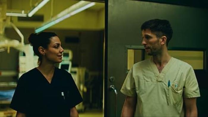 Berlin ER TV show screenshot: two doctors, a White man and a darker-skinned woman look at each other