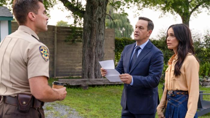 Best Medicine TV show screenshot 2: A police officer confronts Dr. Martin and Louisa in a park; Dr. Martin holds a paper defensively
