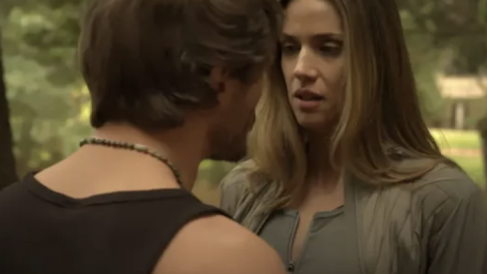 Between Father and Son TV show screenshot 1:Two people standing close in a wooded area, engaged in serious conversation.