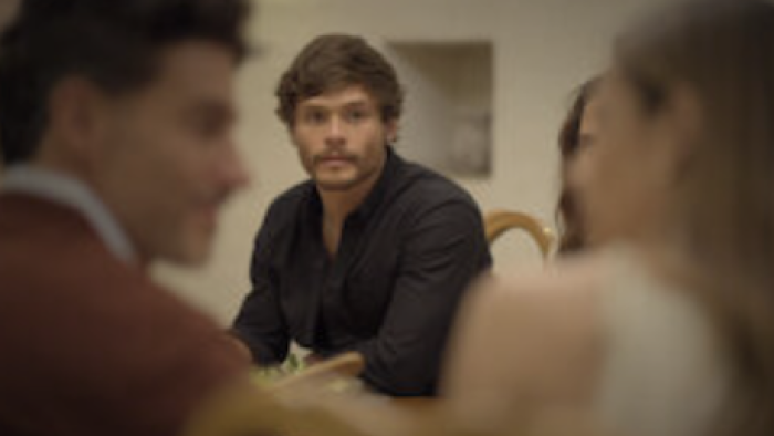 Between Father and Son TV show screenshot 2:Man in a black shirt looks thoughtfully at a couple in the foreground.