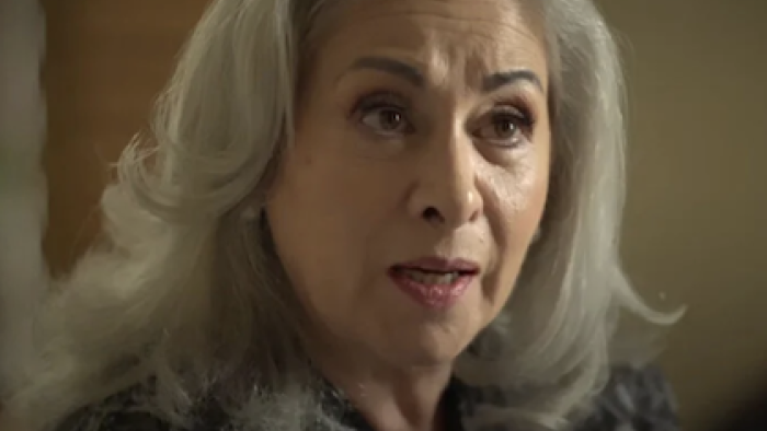 Between Father and Son TV show screenshot 3:Elderly woman with gray hair, wearing a dark patterned shirt.