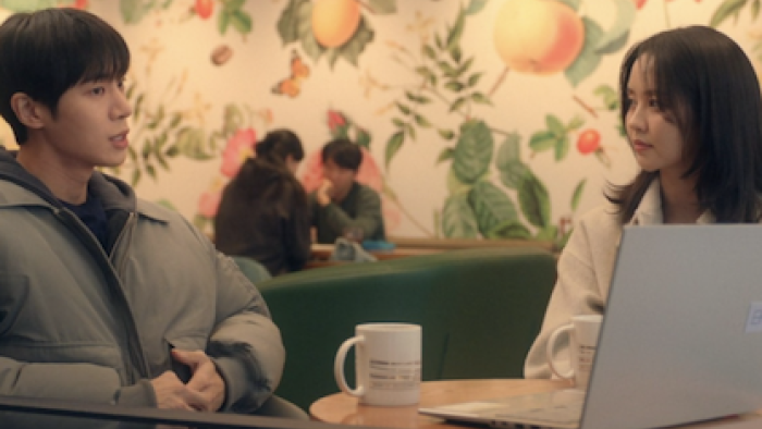 Between Steps TV show screenshot 2: Park Min-Jae talks to Im Yu-jin at table with coffee mug and laptop.