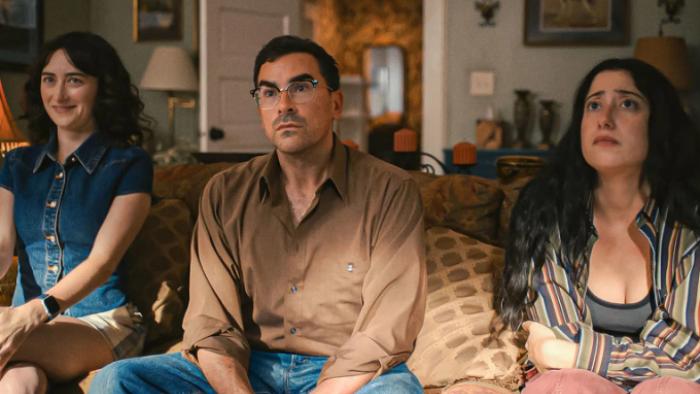 Big Mistakes: Nicky, Morgan and Natalie sit on a sofa in a living room, looking up at something off-camera; their facial expressions are bemused