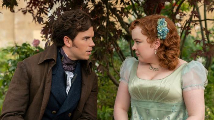 Bridgerton Season 3 TV show screenshot 2: Colin and Penelope sit together on a bench outdoors, looking deeply into each other's eyes