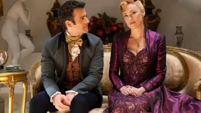 Bridgerton Season 3 TV show screenshot 3: Benedict and Lady Arnold have a discussion on a velvet sofa; both wear serious expressions on their faces