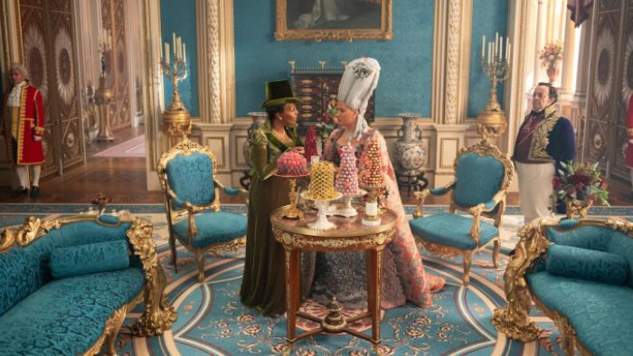 Bridgerton Season 4 TV show screenshot 1: Queen Charlotte stands in front of a table full of bonbons in a room with Brimsley and Lady Danbury