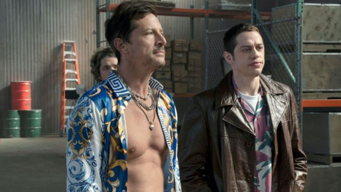 Bupkis TV show screenshot: Pete and a friend stand in a living room together; Pete wears a leather jacket, his friend wears a shirt open to the waist