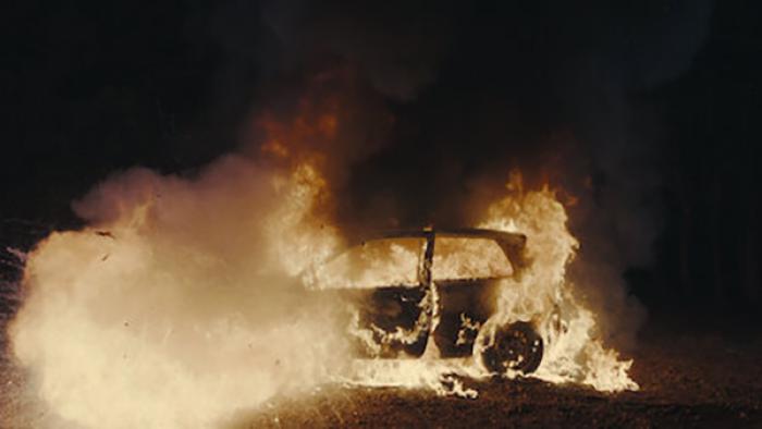 Burning Body TV show screenshot 2: A car engulfed in flames in the dark.