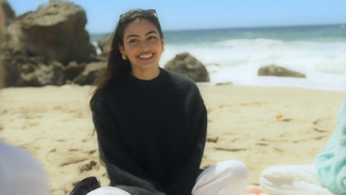 Calabasas Confidential TV show screenshot 1: Nicole Sahebi sits on beach wearing black sweater.