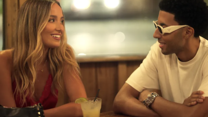 Calabasas Confidential TV show screenshot 2: A woman and a man smiling at each other in a dimly lit restaurant.