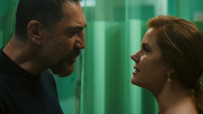 Cape Fear TV show screenshot 3: Javier Bardem and Amy Adams stand inside a hospital room. Bardem wears a dark shirt, Adams wears earrings.