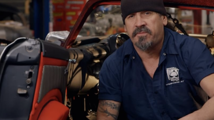 Car Masters: Rust to Riches screenshot 1: Mark Towle sits in open car door of red car. 