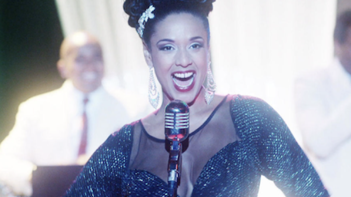 Celia TV show: Jeirmarie Osorio plays young Celia performing in nightclub in sparkling dress with white jacketed orchestra in back.