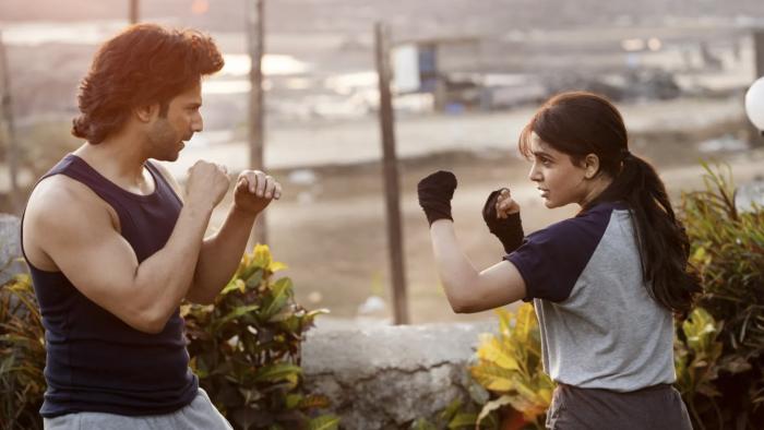 Varun Dhawan and Samantha Ruth Prabhu hold their fists up towards each other, practicing fighting. They both wear athletic gear.