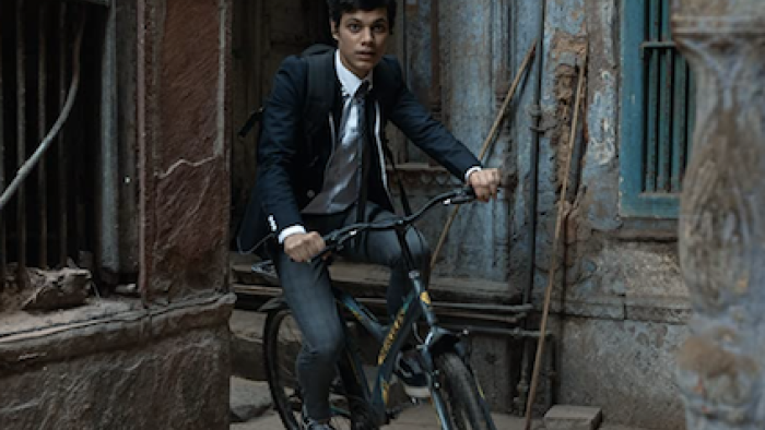 Class TV show: Dheeraj Valmiki rides his bike through the alleyways of his poor New Delhi neighborhood. 