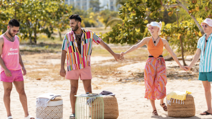Couple to Throuple screenshot 3: Cast members hold hands on the beach.