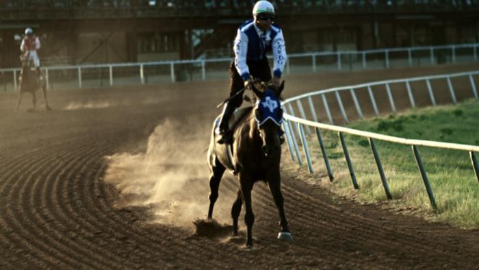 Cowboy Cartel TV show screenshot: A jockey races a horse down a track