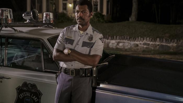 Crystal Lake TV show screenshot 2: Police chief Levon Books stands by patrol car at night, arms crossed, serious expression.