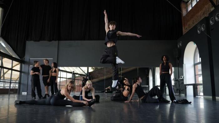 Dance Life TV show screenshot 1: Inside a dance studio, one dance leaps into the air while several pose on the ground
