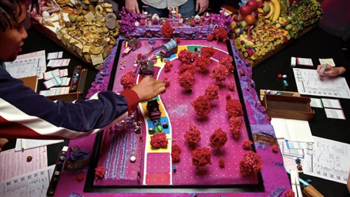 Dimension 20 TV show screenshot 3: Overhead shot of the game table for the season "A Crown of Candy" shows pink mini-trees and a colorful path