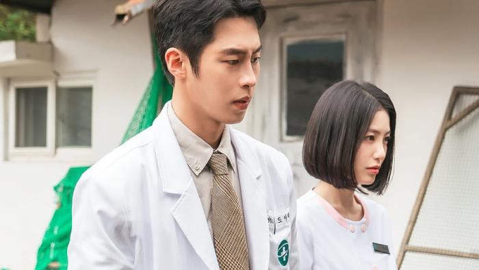 Doctor on the Edge TV show screenshot: A Korean man and woman in white medical uniforms outside, looking focused.