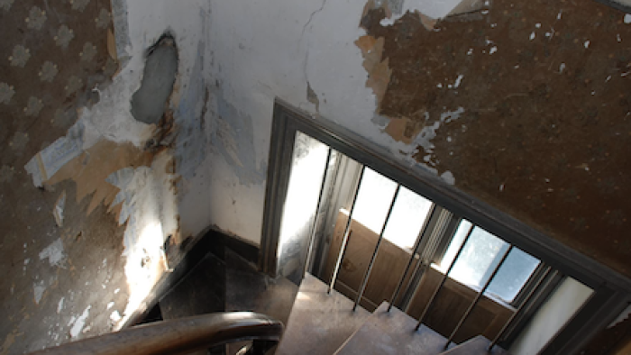 Escape to the Chateau TV show screenshot 3: Spiral wood staircase with peeling wall paper on walls around window.