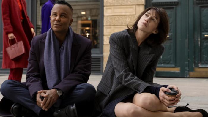Étoile TV show screenshot 1: Genvieve and Raphael sit on the floor of a rehearsal room, looking at something off-camera that's dismaying. 