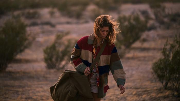 Euphoria Season 3: Rue is shown against a desert background, holding a duffel bag and appearing exhausted