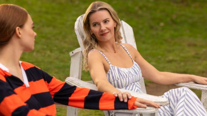 Every Year After TV show screenshot 3: Sue and 13-year-old Percy sit on Adirondack chairs on a wide green lawn, talking together