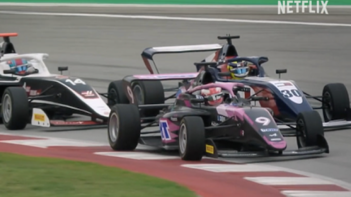 F1: The Academy TV show screenshot 1: A race car tails another race car during race. 