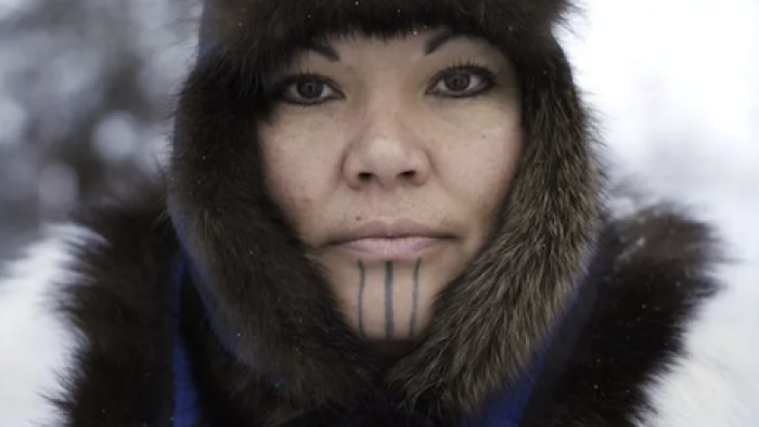 First Alaskans: Jody Potts-Joseph wears brown fur hood, white jacket, and vertical tattoos on chin.
