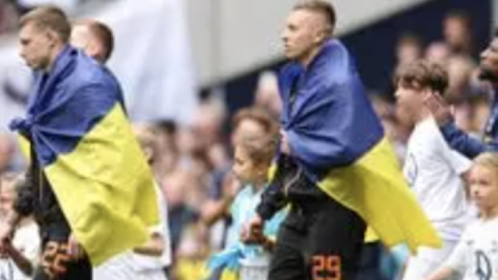 Football Must Go On TV show screenshot 2: Players take the field wearing blue and yellow flags. 