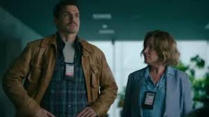 From Tomorrow TV show screenshot: A man and women stand next to each other wearing badges around their necks