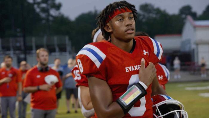 God. Family. Football TV show screenshot: A young black man looks into the horizon while pulling down his football shirt.