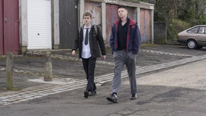 Half Man screenshot 2: Mitchell Robertson and Stuart Campbell walk down the street. Robertson wears a school uniform, Campbell wears sweatpants.