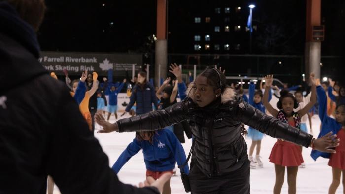 Harlem Ice TV show screenshot 2: Coach stands in an ice rink filled with young black girls, directing the kids through practice.