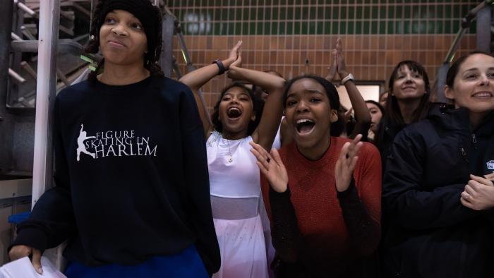 Harlem Ice TV show screenshot 3: Ashley and her teammates stand on the sidelines excitedly applauding the action on the rink