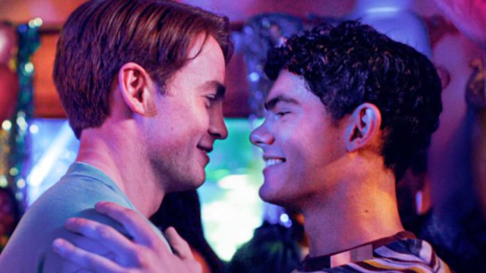 Heartstopper Forever TV show screenshot 1: Nick and Charlie are shown in closeup in a neon-lit club; their faces are close together